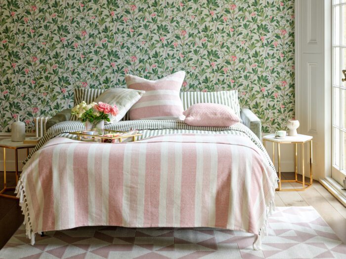 A sofa bed with a pretty throw and cushions on it