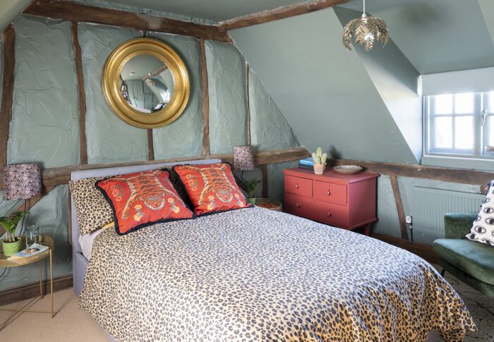 The second spare bedroom has Farrow & Ball’s Green Smoke on all the walls between the beams, Leopard Love bedding from Rockett St George and stunning Paloma Faith cushions. ‘I’ve carried on the red accent with an upcycled cupboard paint in Good Homes Fulham flat matt furniture paint at B&Q.’ 