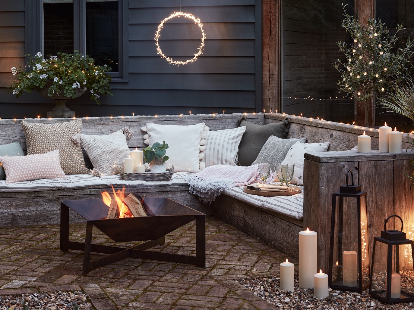 Patio at night with corner sofa, LED candles and fire pit