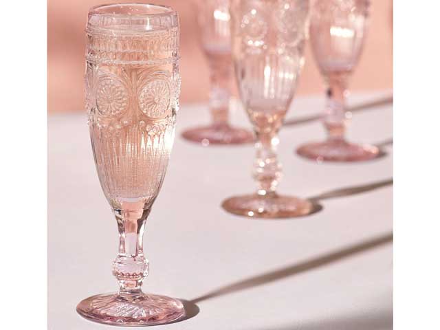 next embossed champagne flutes on a table with pink background