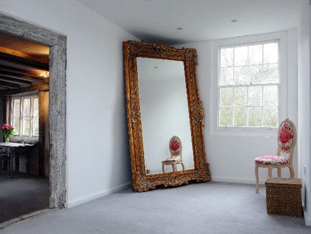 room with large freestanding mirror in frame sash window and chair