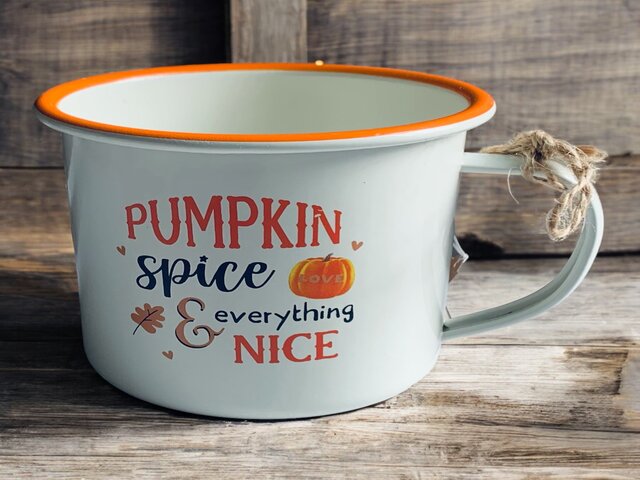 Pumpkin spice and everything nice white enamel mug with orange and black writing on wooden surface