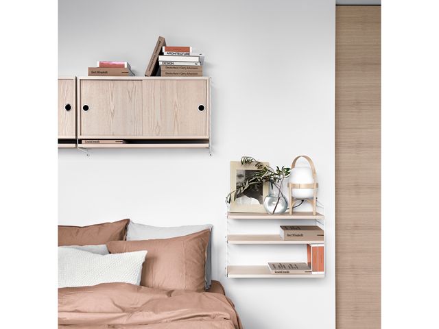 skandium bedroom shelving by a bedside with a plant, books and reading light, instead of a bedside table