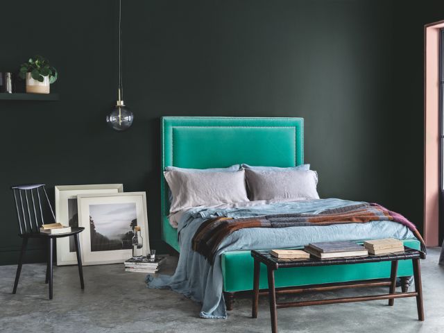 Green bed with black painted walls in a bedroom